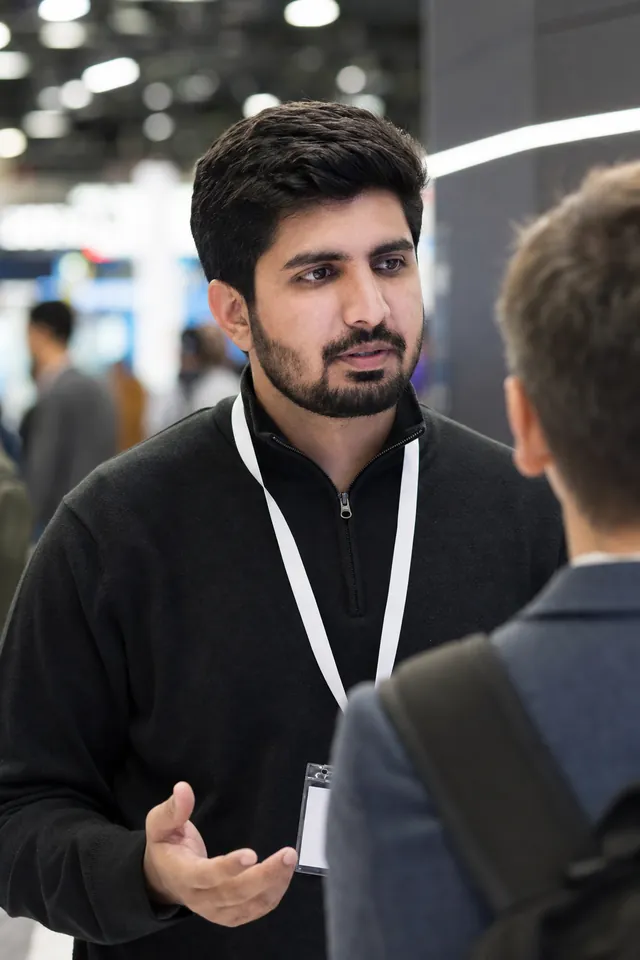 Hassaan Bukhari talking with a visitor at a technology expo