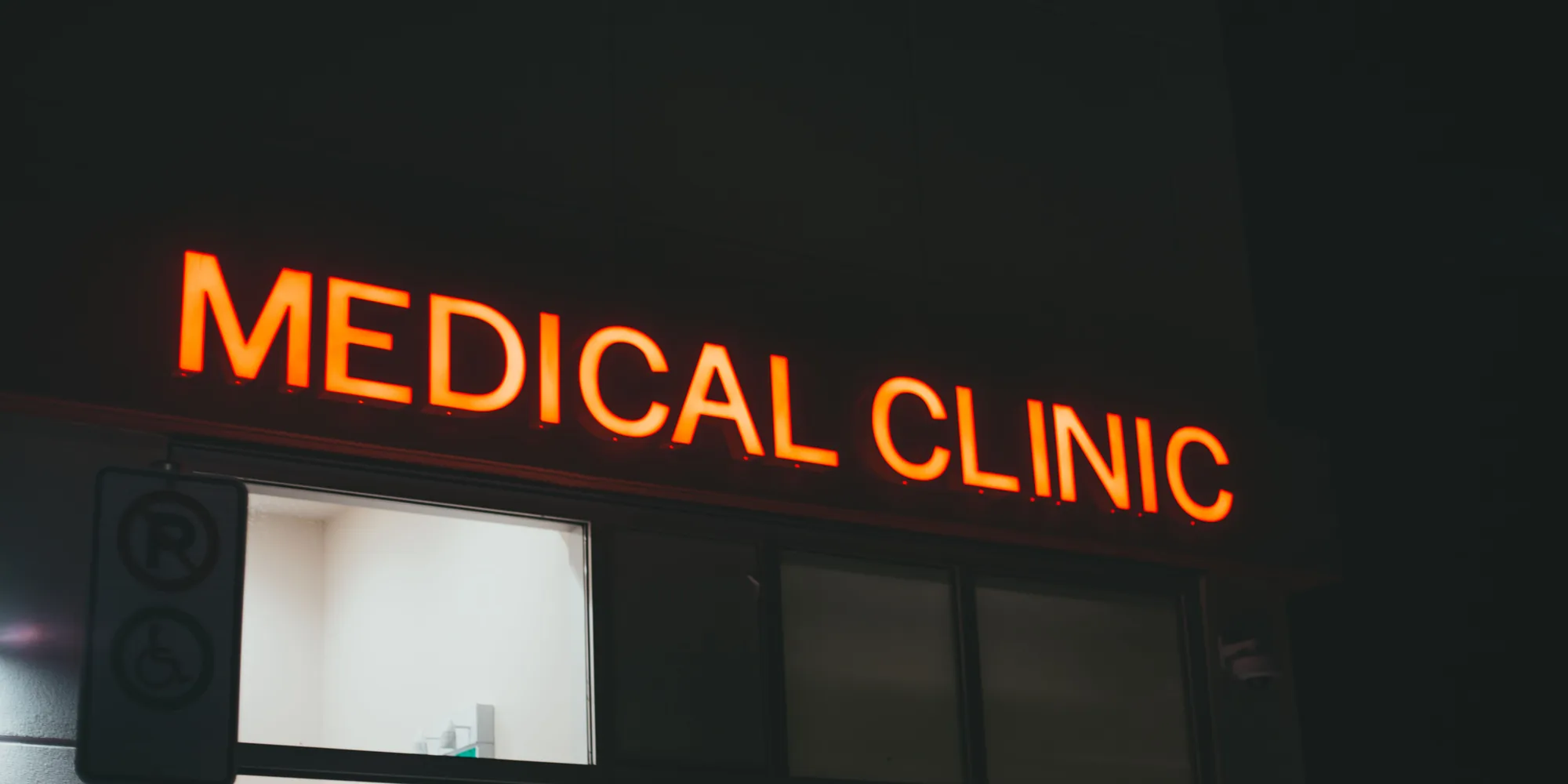 An illuminated medical clinic sign above a doorway at night