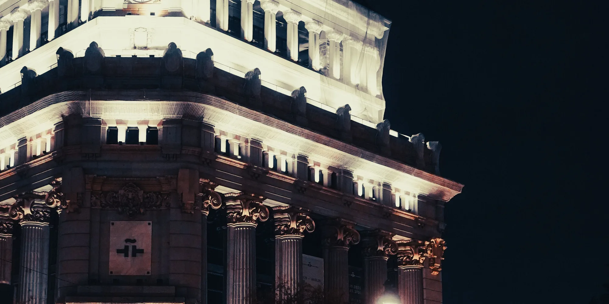 A neoclassical civic building lit against a dark sky at night
