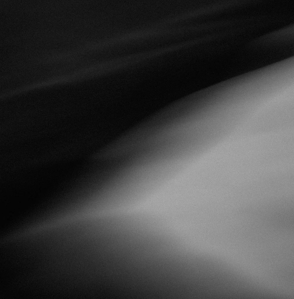An abstract three dimensional render of a soft dark fold catching light