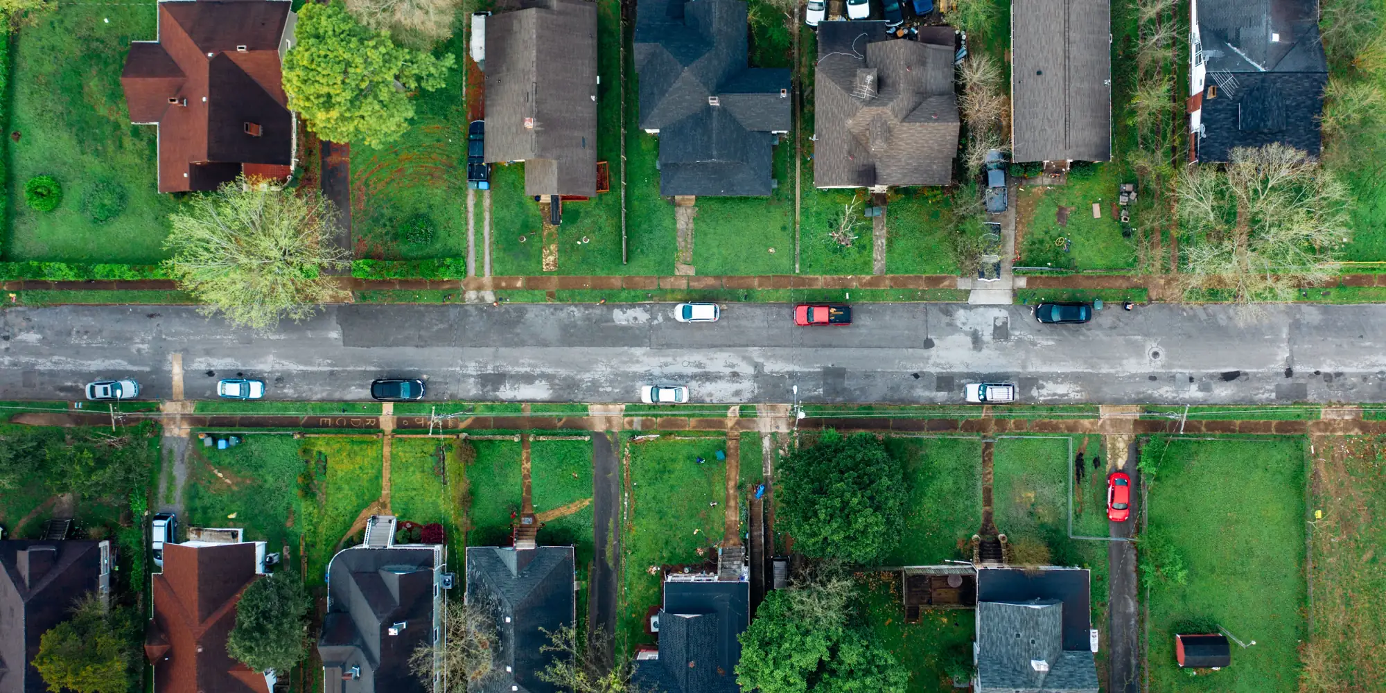 A view from directly above a residential street lined with houses and gardens