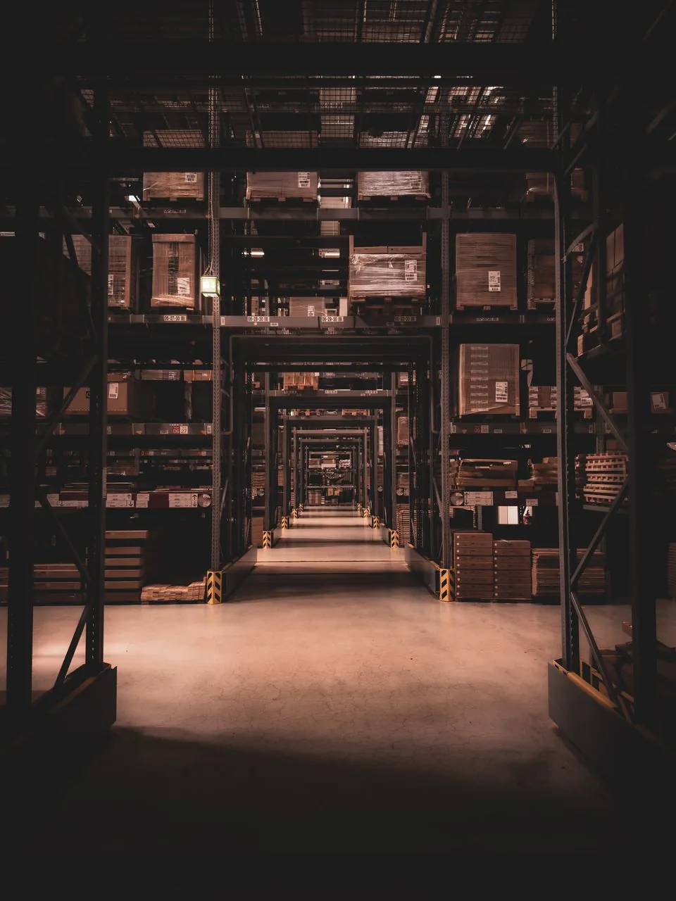 A warehouse aisle at night with racking either side and the floor lit ahead