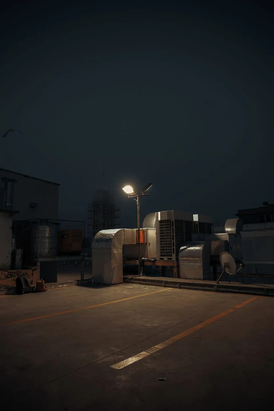 Rooftop air conditioning units at dusk beneath a street lamp
